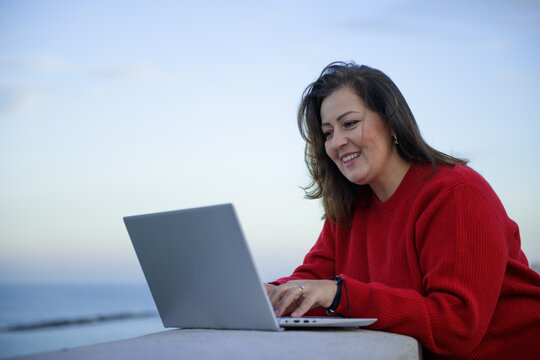 Smiling woman working on the laptop in the evening