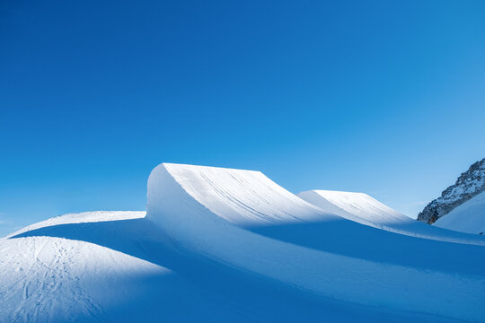 Sunset lights on big air jumps in snow park.