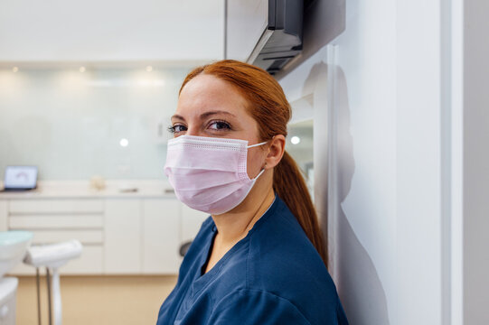 Dentist in a Modern Clinic Wearing Protective Mask and Scrubs