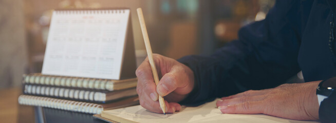 Planner or organizer writing daily appointment On Calendar book and using smartphone. Asian woman hand plan timetable meeting agenda and note schedule business in diary. Planner concept-banner image.