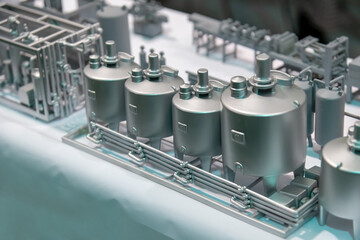 Scale model showcases various industrial tanks and machinery in a well-lit exhibition hall. This intricate display highlights engineering design and innovation.
