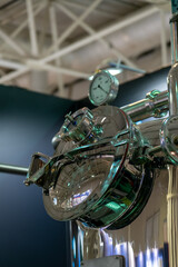 Obraz premium Close-up view of large shiny metal tank in food processing factory. Milk, juice, beer or wine production line. Soft focus. Modern industrial equipment theme.