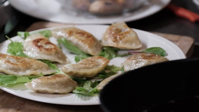 Serving  freshly pan-fried pierogi onto a plate garnished with greens