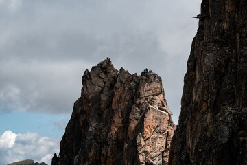 Group of climbers on a dramatic rock peak in the French Alps with moody skies.