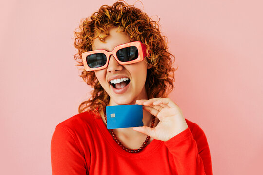 Excited woman showing credit card in studio