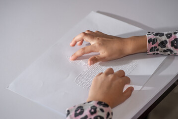  Child tries out Braille on a page with her fingers