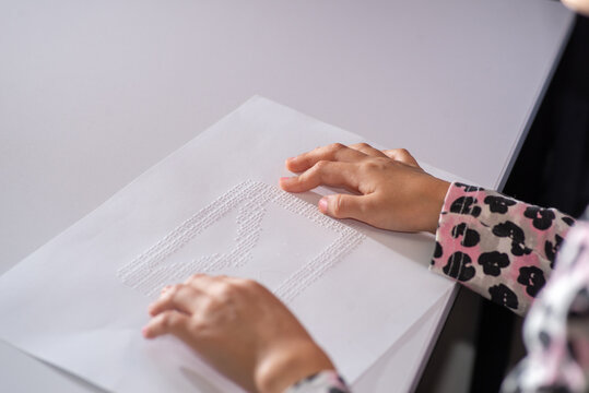 Child tries out Braille on a page with her fingers