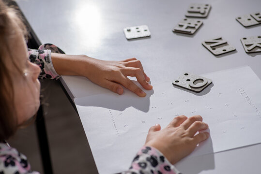 Child tries out Braille  multiplication table with her fingers