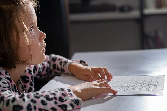 Child tries out Braille  multiplication table with her fingers