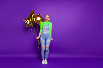Full size photo of cute lady holding baloon wearing yellow turtleneck denim jeans overall isolated over purple violet background