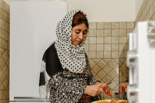 Afghan woman peeling a carrot at the kitchen