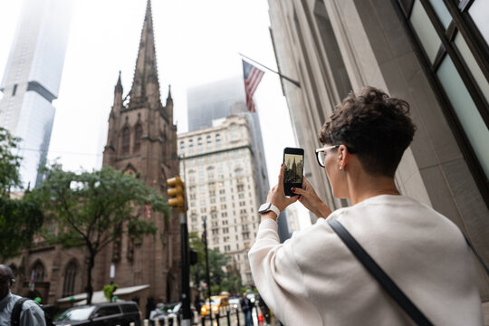 Tourist taking pictures of trinity church in manhattan, new york city