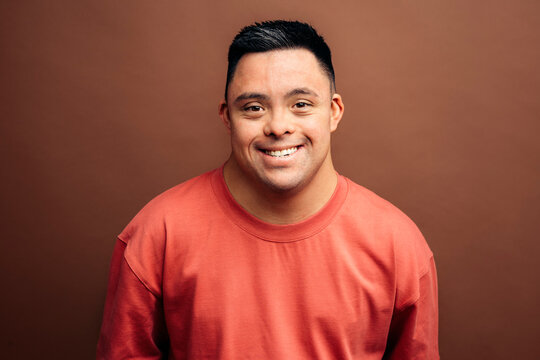 Man with Down syndrome smiling on brown background