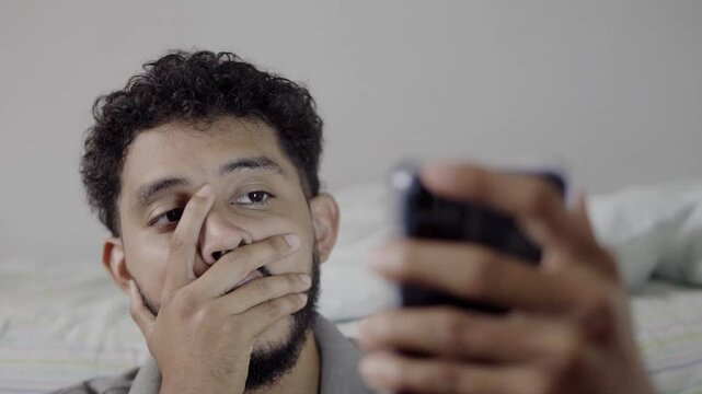 Hispanic man expressing frustration and despair while using smartphone