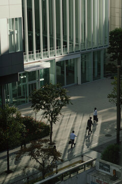 People walking along a modern building with large windows in Japan