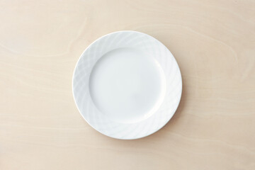 Empty white plate on wooden table. Top view.	