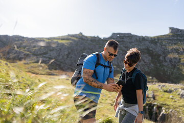 Hikers using smartphone gps app while hiking in mountain landscape