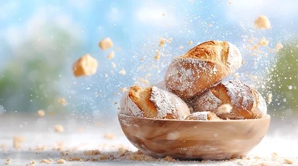 Gordijnen Freshly baked bread rolls in a wooden bowl with crumbs flying, against a bright background. © mtsbraja