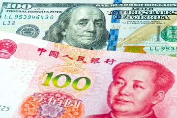 100 US dollars and 100 Chinese yuan banknotes. International trade concept.