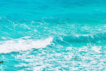 Naklejka premium Turquoise waves of Caribbean Sea with white foam creating vibrant natural pattern on water surface. Mexico.