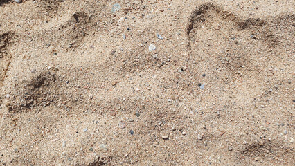 Stones and sand in the summer day. Yellow sand on the beach near a sea.
