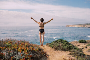  Woman Embracing the Ocean on Coastal Cliff