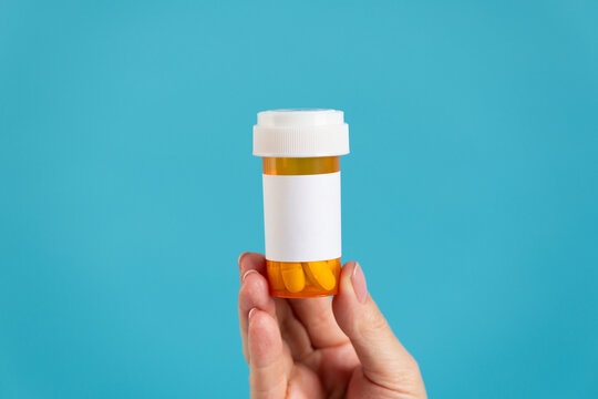 Hand holding prescription pill bottle. Mock up, blank label. 