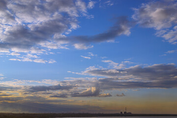CHP and other plants stand on the shore of the lake in the evening at dusk under the evening sky