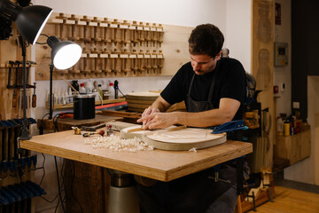 Young luthier crafting a flamenco guitar in a workshop