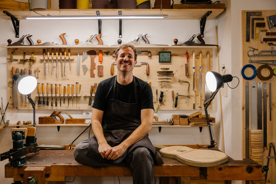 Young luthier crafting Spanish flamenco guitars in workshop