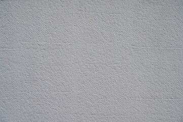 A textured gray wall showcases various subtle shades and patterns, representing an industrial design element often found in urban settings during daylight