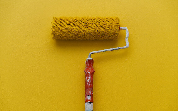 A paint roller rests on a Yellow wall