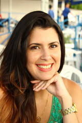 Smiling girl, with a green t-shirt, gold watch, black hair and smiling at the photographer