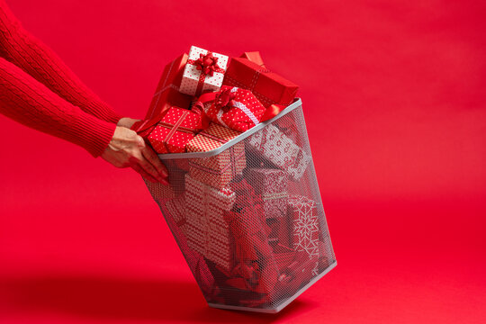 Person holding trash can full of Christmas presents and gifts. 