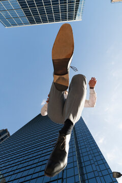 Businessman leaping against skyscrapers