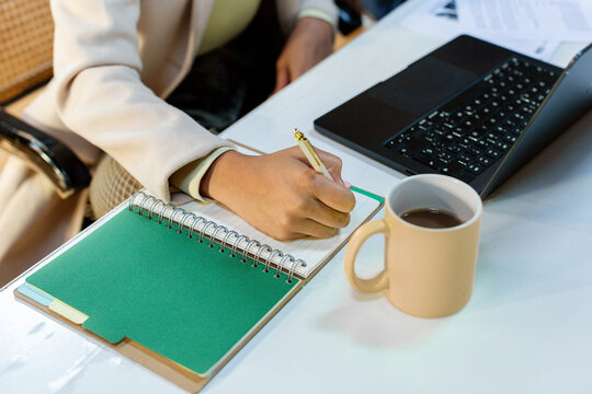Crop of businesswoman's hand taking notes in work meeting 