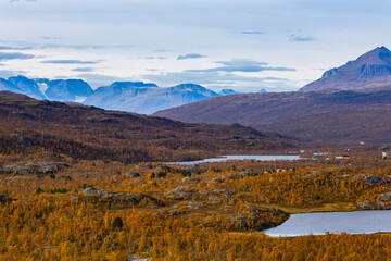 Autumn landscape of Kilpisjarvi, Finland, showcasing colorful foliage, serene lakes, and majestic mountains in the background.
