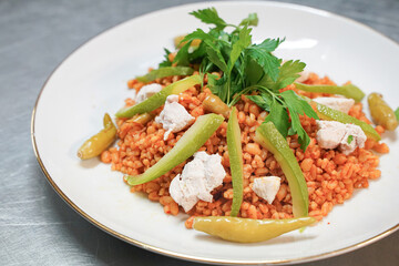 Nutritious bulgur pilaf with tomato paste garnished with greens, close-up