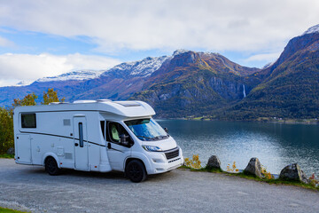 A motorhome parked by the serene Lustrafjorden in South Norway, with stunning mountains and a waterfall in the background. © Alberto Gonzalez 