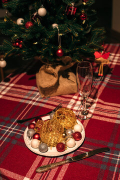 Christmas tree and plate with colorful festive balls are the table.