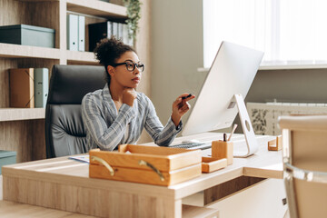 Focused, serious African American businesswoman working on computer in modern office