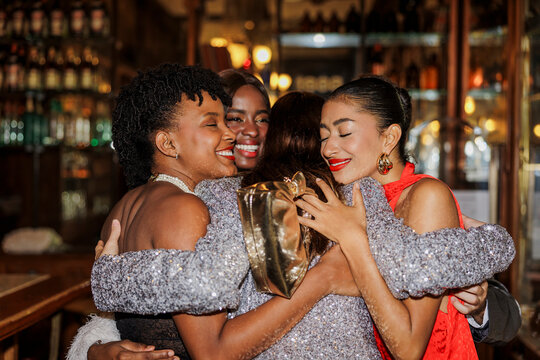 Happy friends hugging and celebrating new year's eve at bar ugc