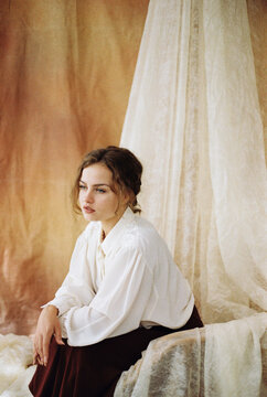 Film photography of woman sitting on armchair against fabric