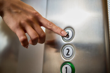 Pressing the elevator button in contemporary high rise buildings signifies modern urban convenience