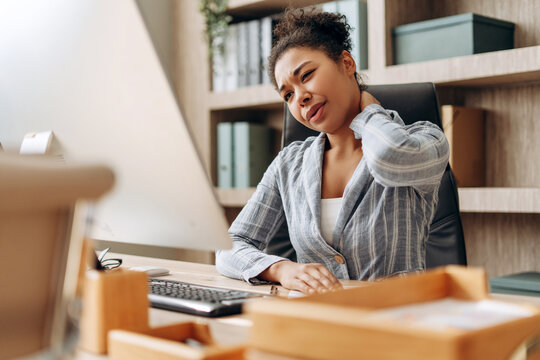 Office worker suffering neck pain at work using computer