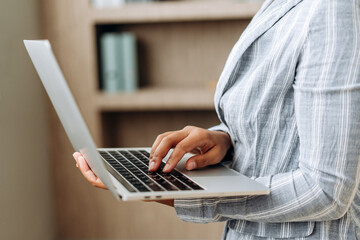 Businesswoman working on laptop in modern office: typing on keyboard