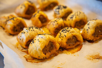 Tradtional puff pastry pork sausage rolls topped with black onion seeds. Organic pork snack. Food photography.