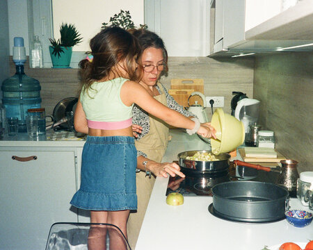 A young mom teaches her young daughter how to cook in the kitchen