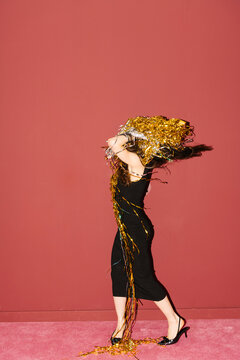 Woman Celebrating with Glitter Confetti Against a Red Wall