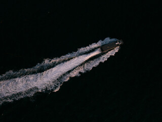 Aerial view of a boat speeding through dark waters.